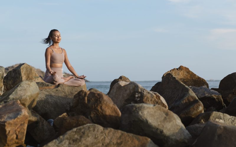 full-shot-woman-doing-yoga-rocks-nature